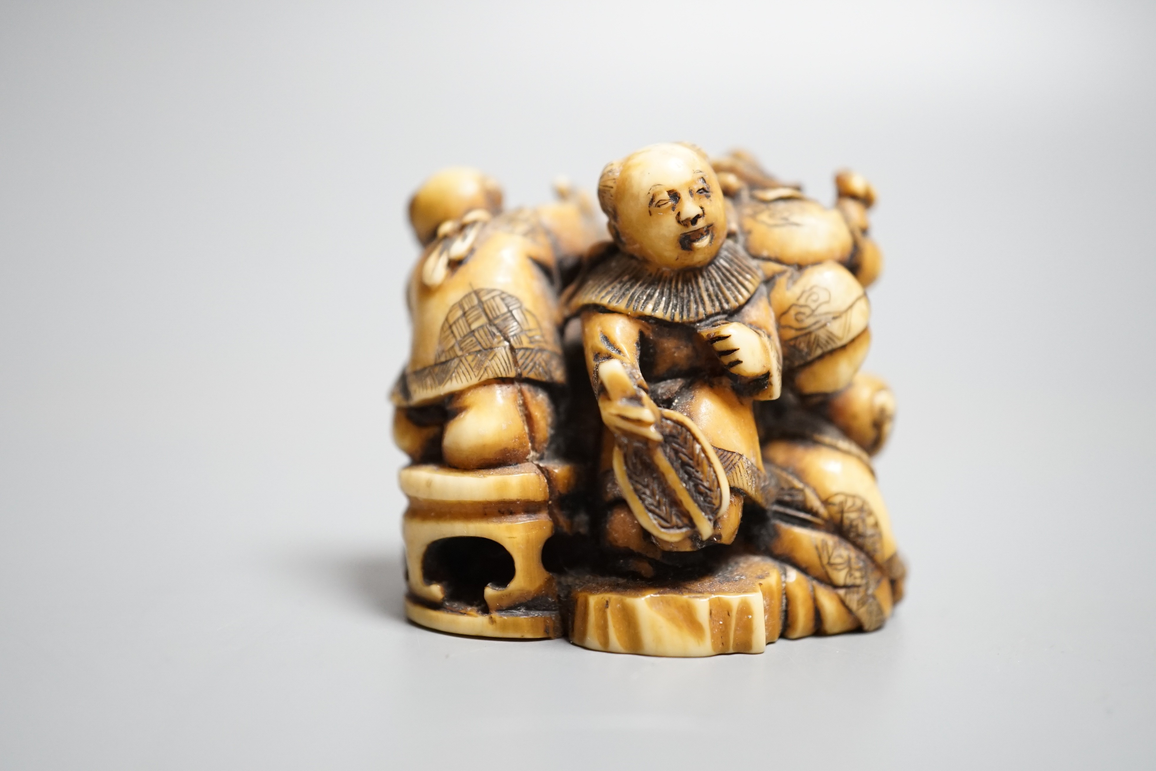 A Japanese ivory netsuke of Hotei with three boys, Meiji period, signed, width 4cm